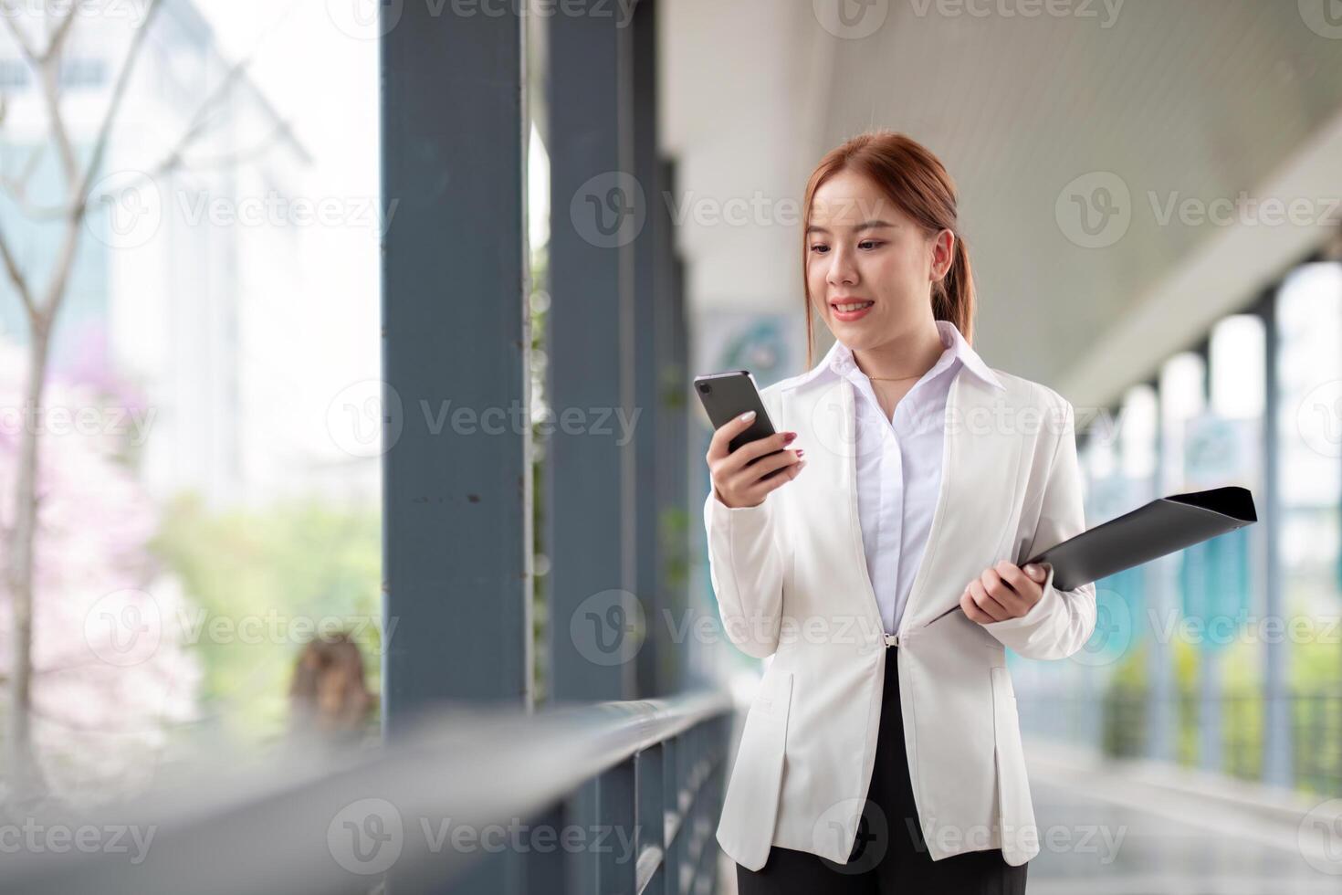 Asian business woman beautiful with smart phone and document file, asian woman with smartphone walking go to work. Preparation for the working day photo