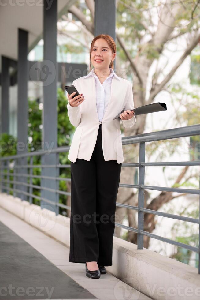 Asian business woman beautiful with smart phone and document file, asian woman with smartphone walking go to work. Preparation for the working day photo
