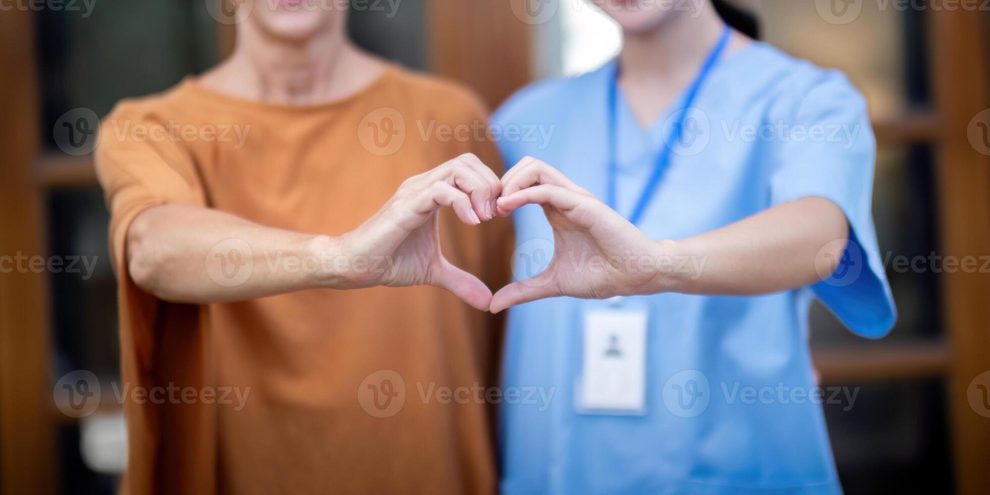 Nurse or caregiver and elderly woman support, healthcare service and health portrait at home. Medical physiotherapy, make a heart shape with your hands together in home photo