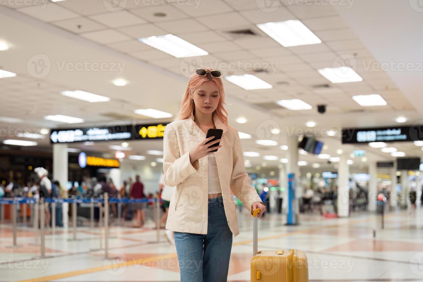 A woman asian walking in an airport. Mobile, suitcase and travel with a young female on an international trip for work or travel photo