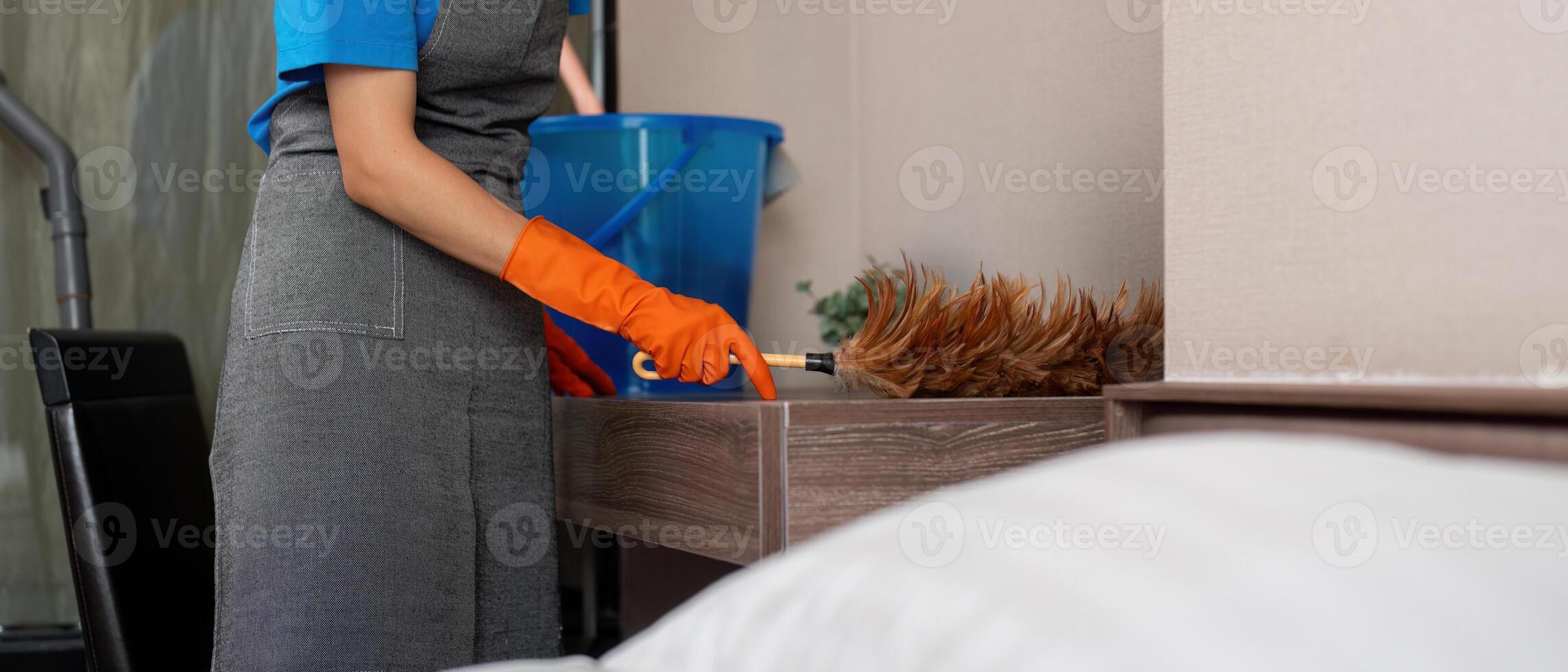 Cleaning service woman worker cleaning in bedroom at apartment. housekeeper cleaner feel happy and use feather duster wiping messy dirty for housekeeping housework or chores photo