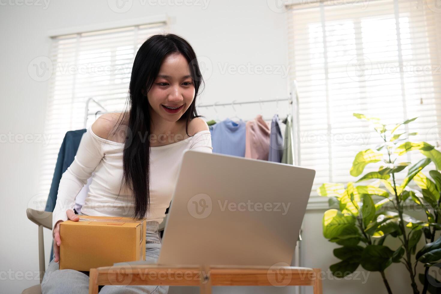 Happy young asian business owner woman prepare parcel box and check online order of product for deliver to customer on laptop computer. Shopping Online concept photo