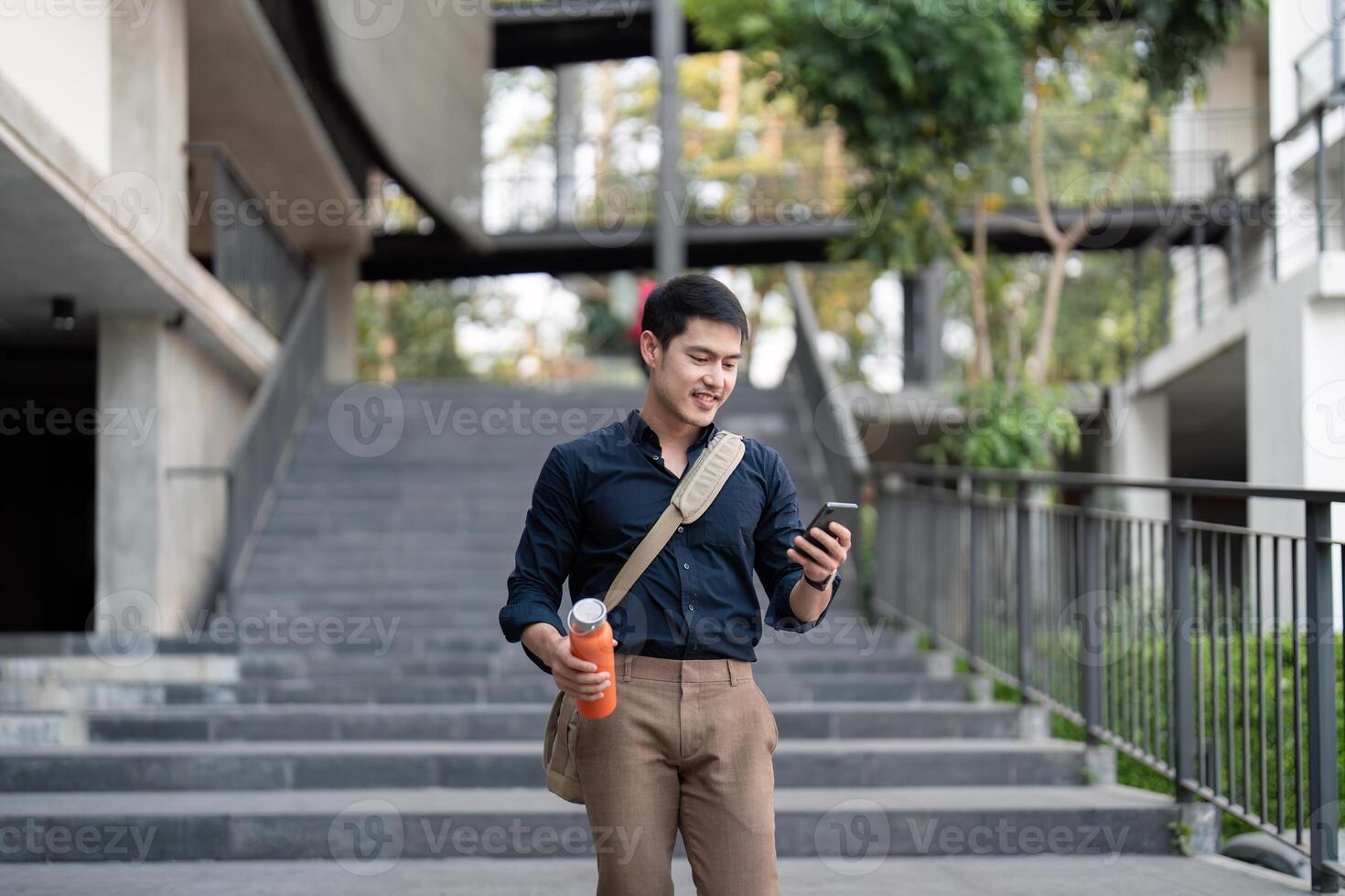Smiling asian businessman walking to work while to hold reusable eco friendly ecological cup in the city photo