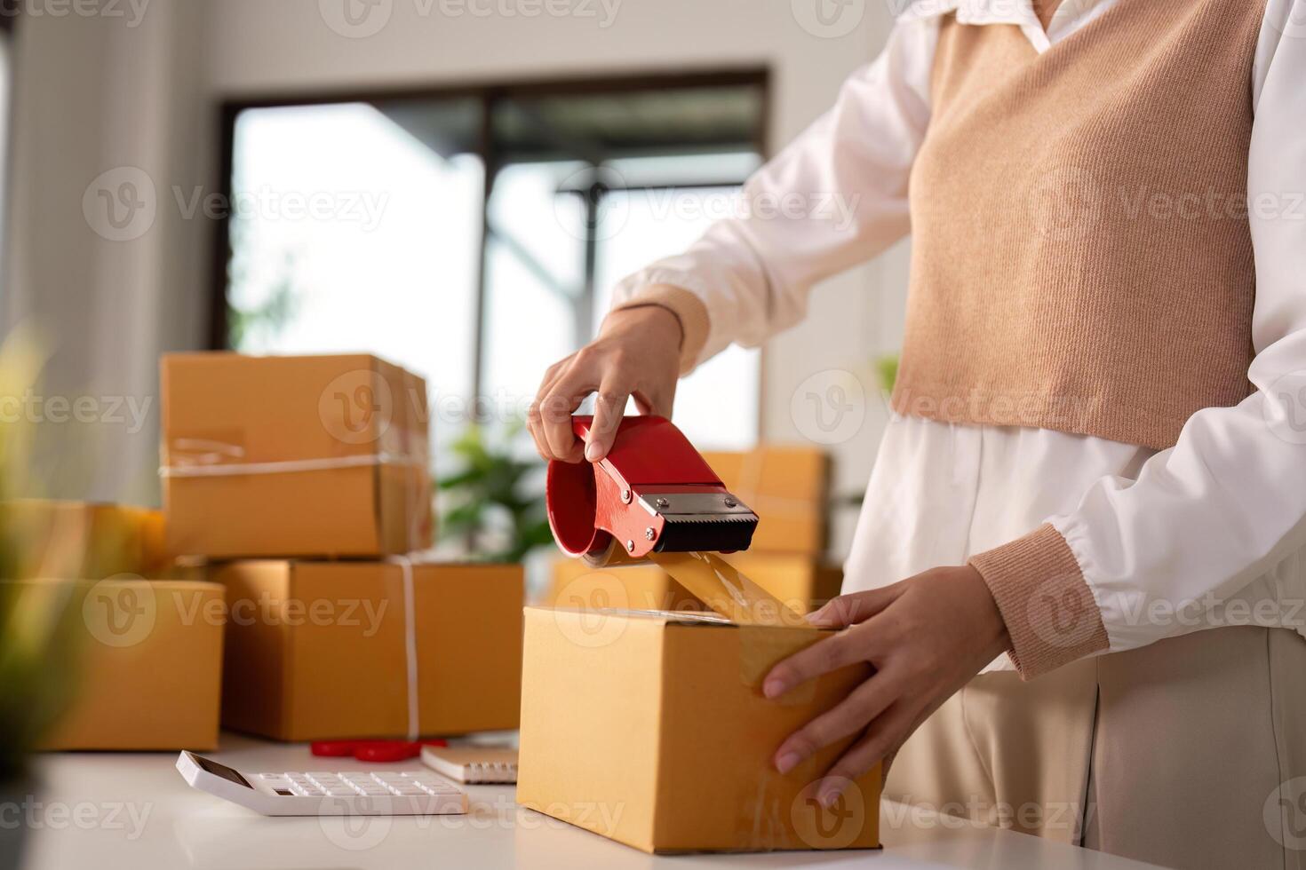 Woman asian use scotch tape to attach parcel boxes to prepare goods for the process of packaging, shipping, online sale internet marketing ecommerce concept startup business idea photo