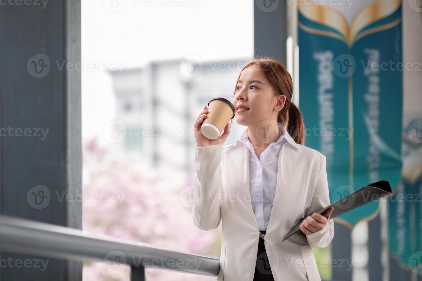 Beautiful successful business woman in walking on the street in business town with coffee and document file. Preparation for the working day photo