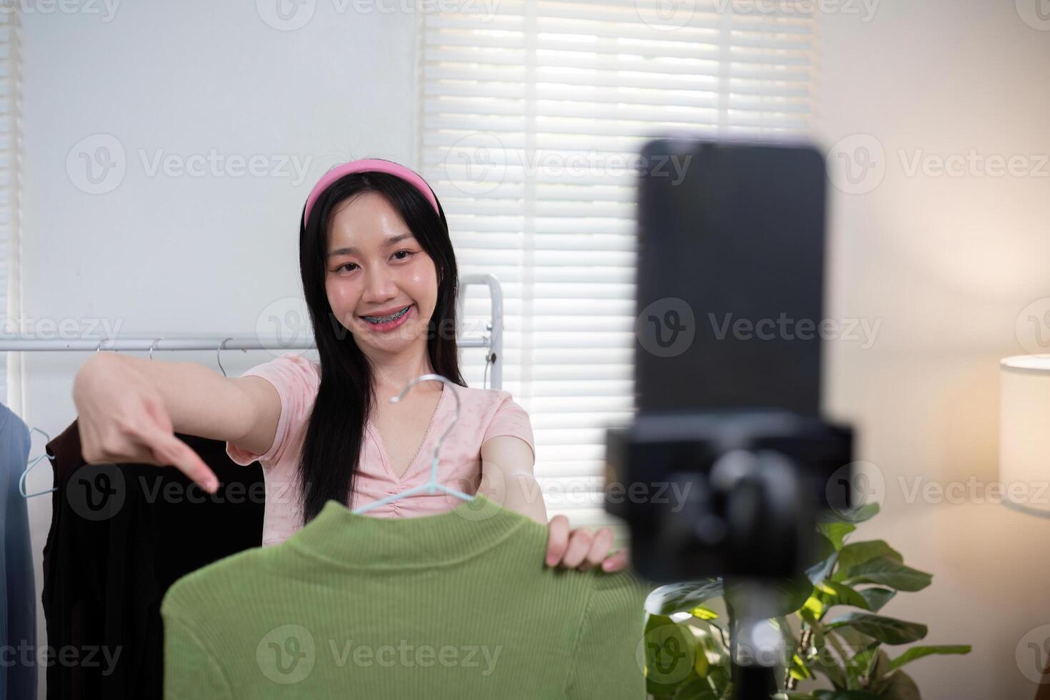 Woman asian online sell is using smartphone to broadcast live on Vlog for introduce new fashion while review shirt collection and talking with customer to selling online clothing on social media photo