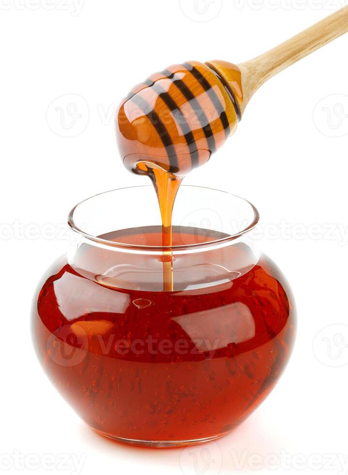 Glass pot and honey stick isolated on white background, honey pouring photo