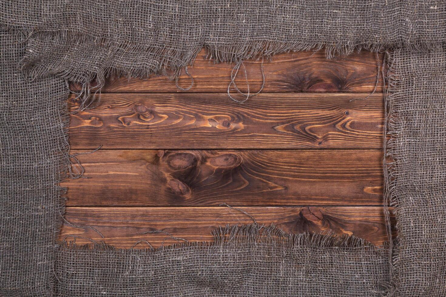 Burlap on dark wooden background, top view photo