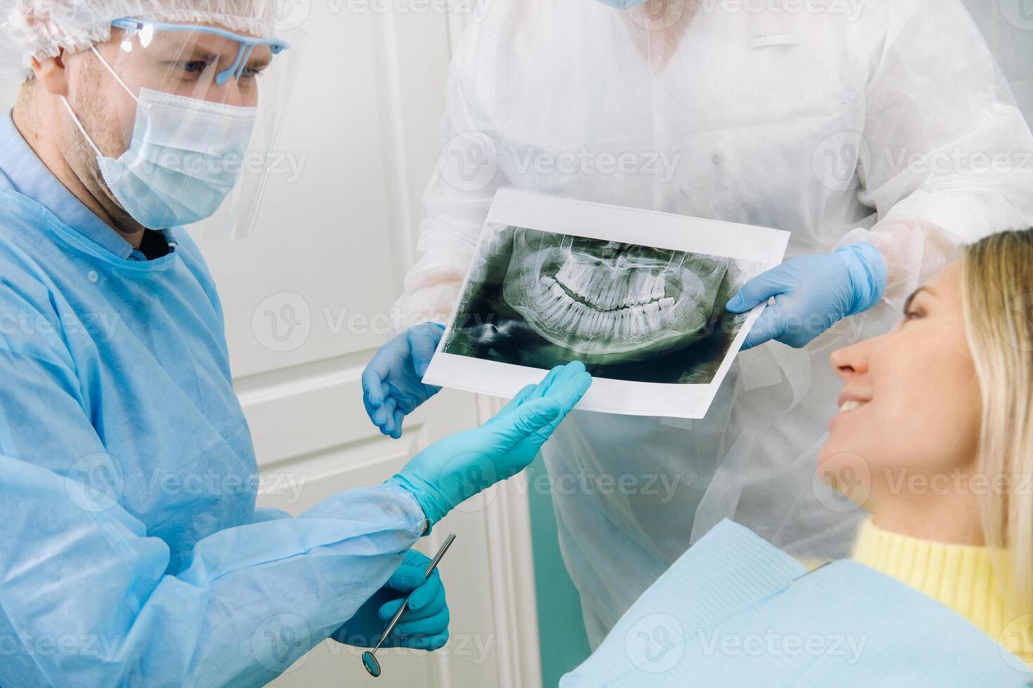 Dentist explaining the details of the X-ray to his patient in the office photo