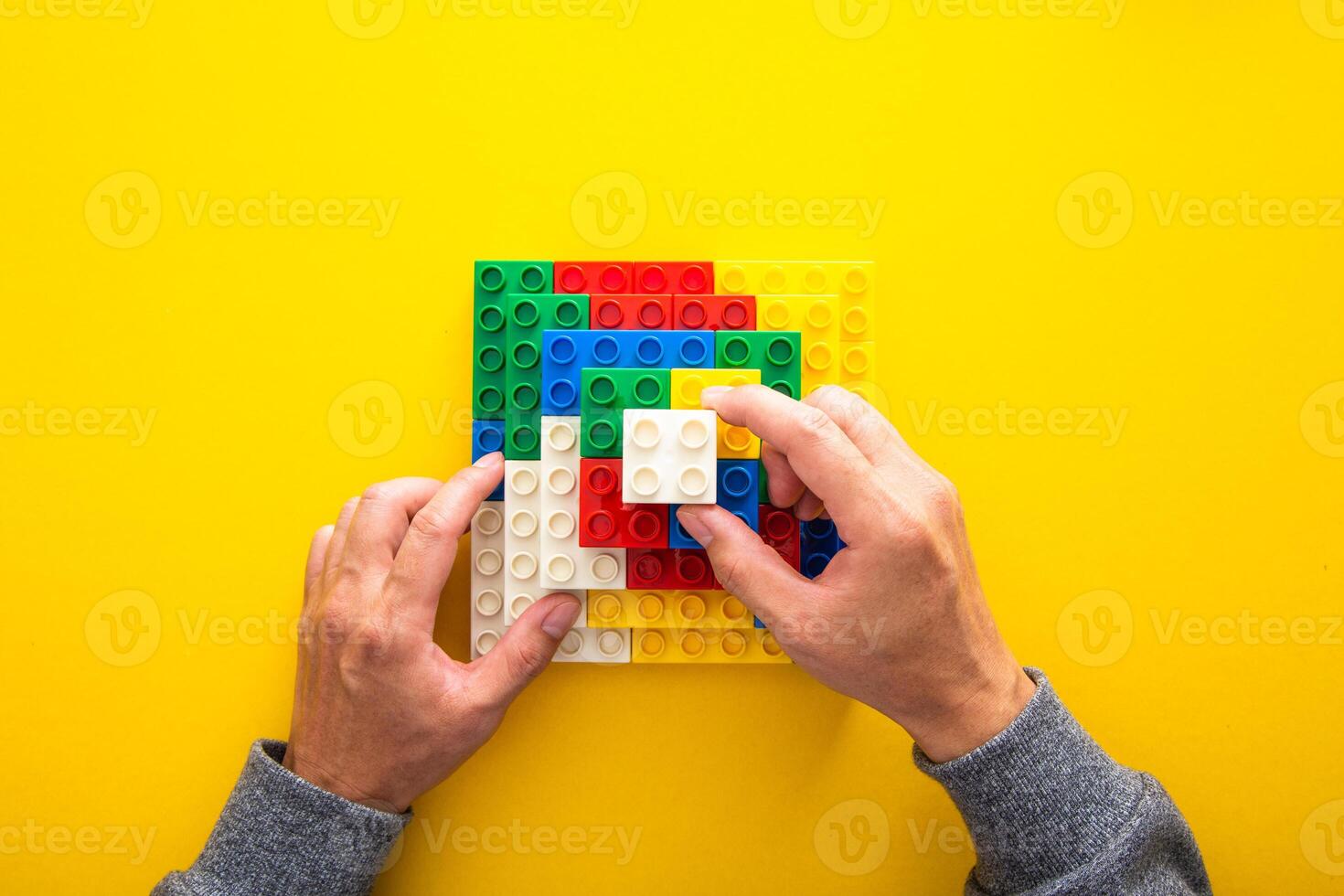 hand stacking up the colorful plastic block on yellow background photo