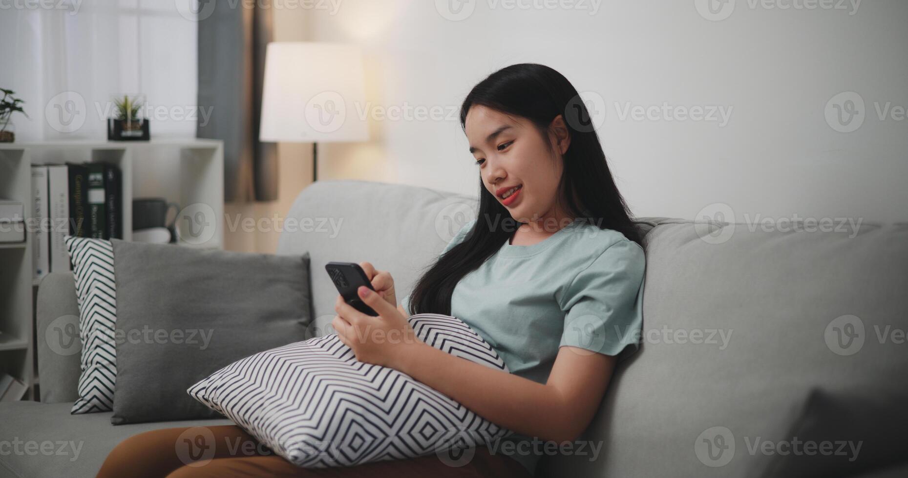 Selective focus ,Happy young woman sitting on sofa enjoy using mobile phone for online shopping cashless in living room at home photo