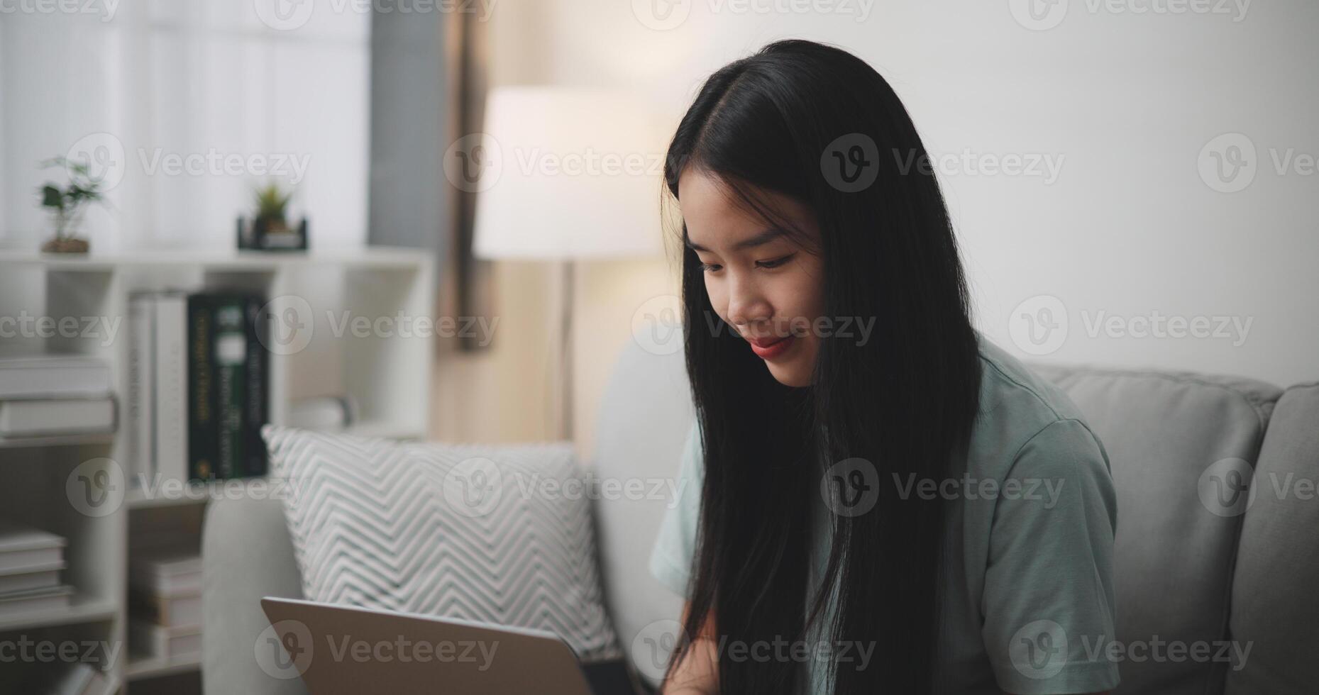 selectivo atención ,feliz joven mujer sentado en sofá utilizando ordenador portátil para en línea compras sin efectivo en vivo habitación a hogar ,Internet conectividad y en línea concepto. foto