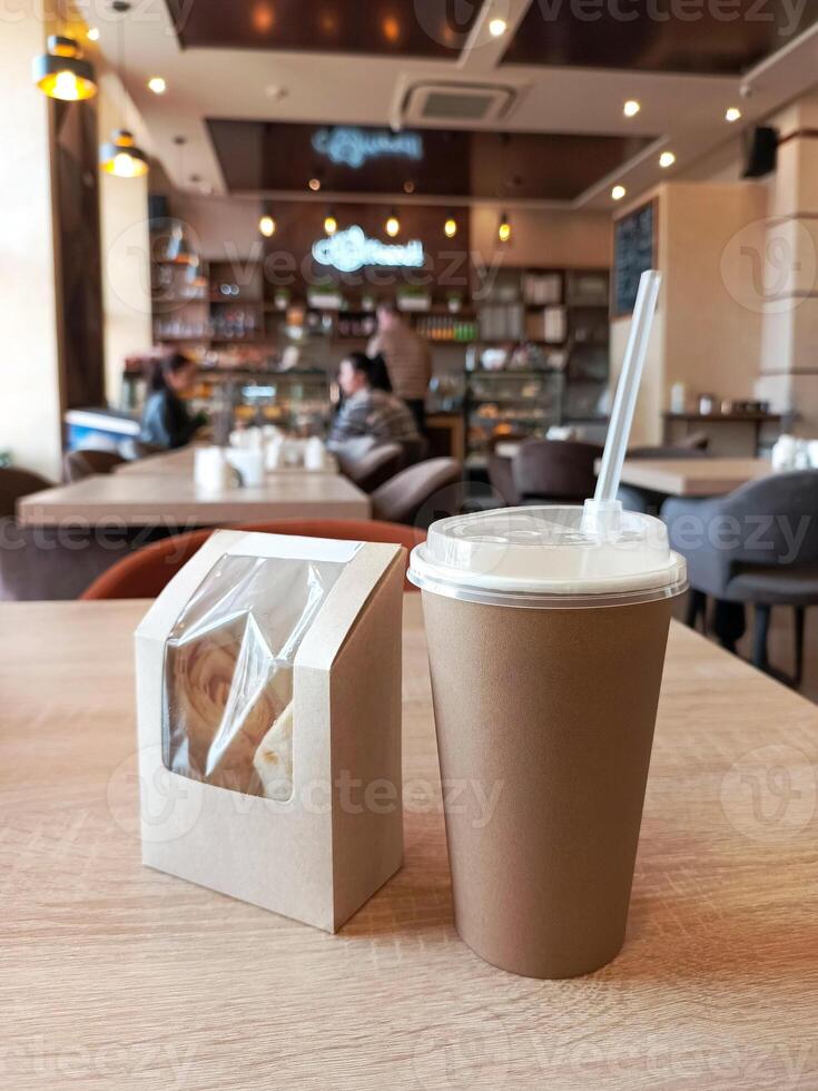 Take away coffee cup and rolls with ham and cheese on a table in the cafe. Dark vending coffee in disposable craft paper cup. mock up template photo