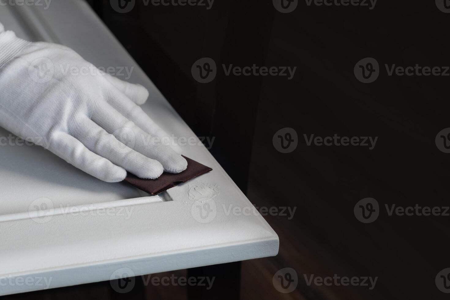 Person remonier worker in a gloves sands a wooden product, kitchen facade with a putty with a sandpaper photo
