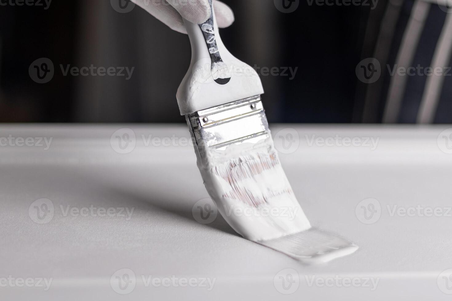 Brush with white paint, a man makes repairs. Painting a wooden product photo