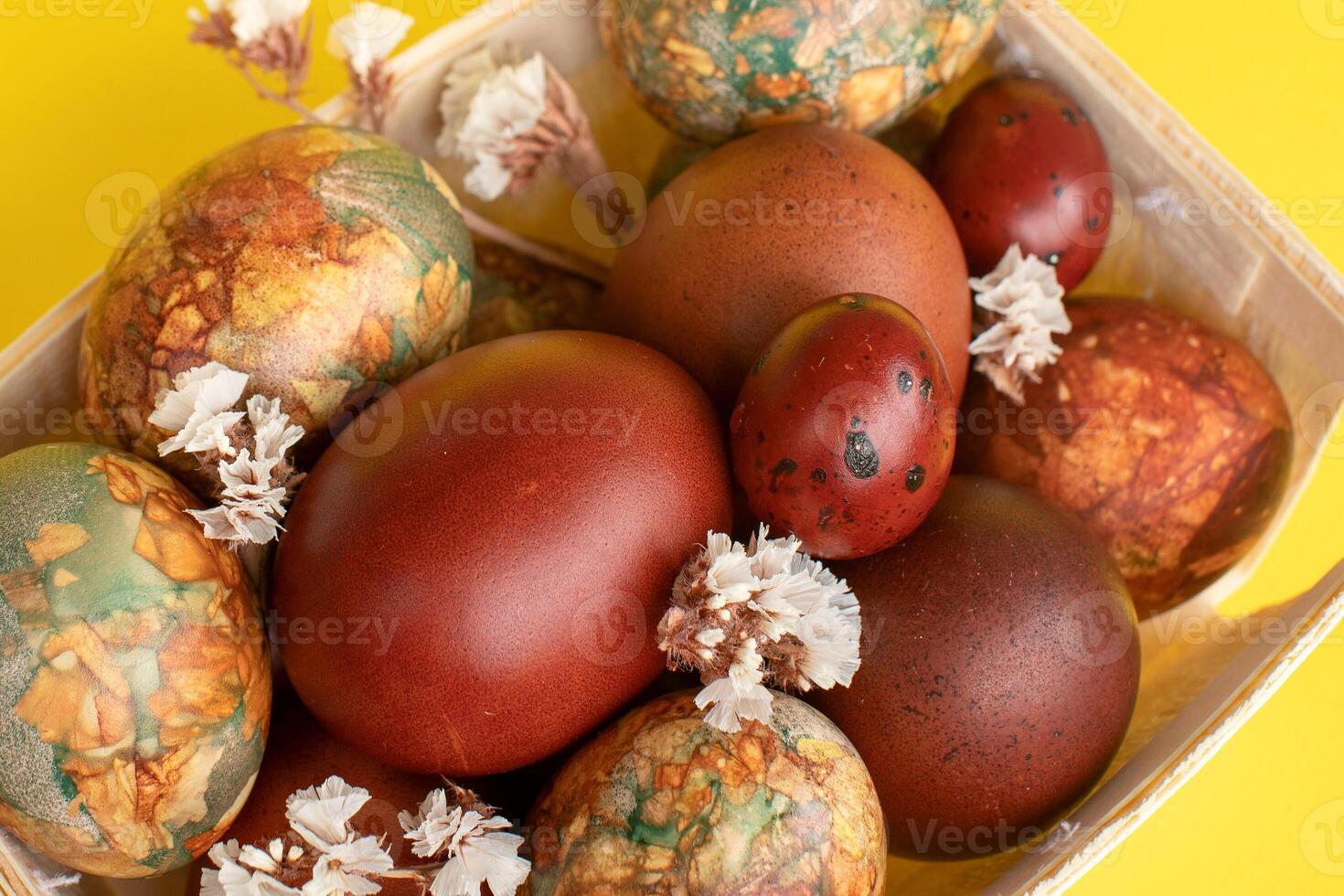 Assortment of Easter eggs with natural leaf patterns in a wooden basket photo