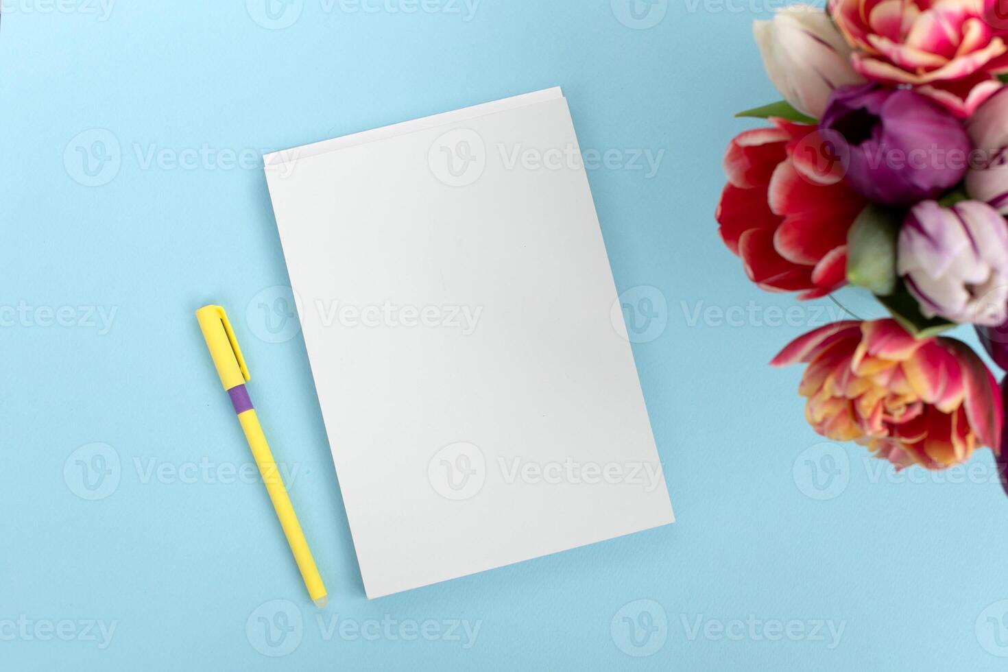 Top view of a blue table with a mockup of blank notebooks with a bouquet of tulips on the side. photo