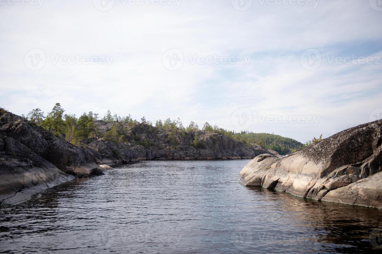 A river flowing in the mountain peaks. The shore is made of stones. Forest on the lake shore photo