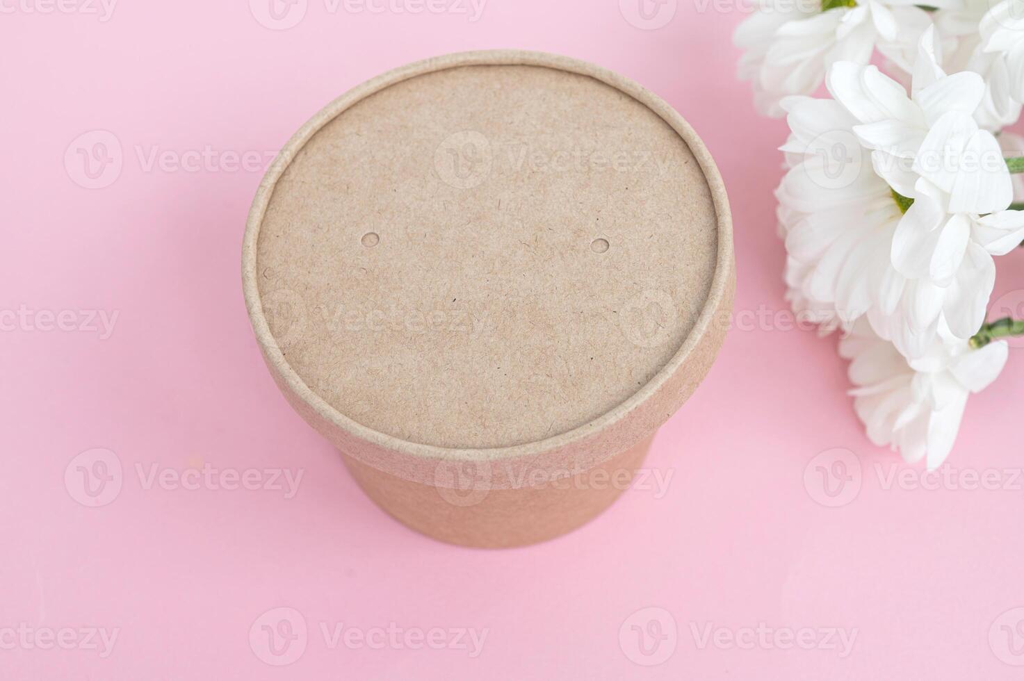 Brown cardboard food container with lid on a pink background with white flowers. photo