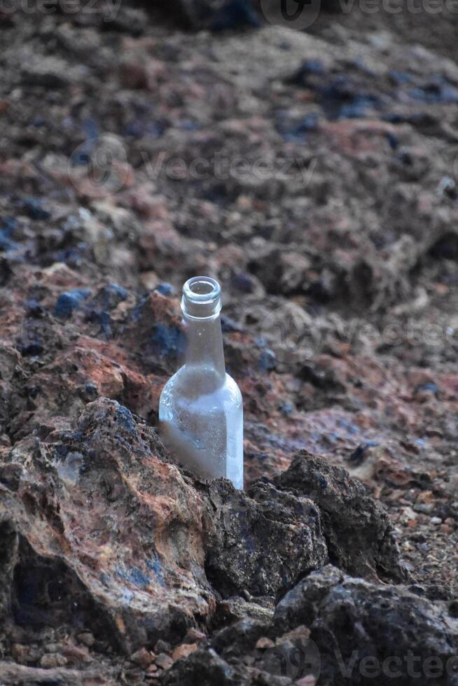 Glass Bottle Sitting on Lava Rock on the Coast photo