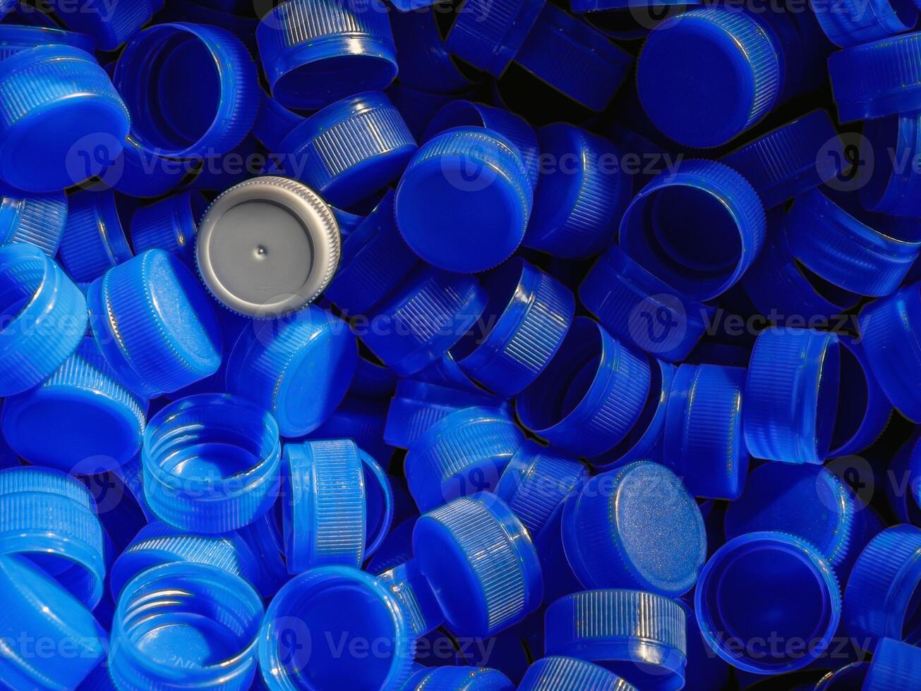 Grey plastic bottle caps on top to depict the concept of standing out from the crowd, dare to be different, odd man out, success or a leadership concept. photo