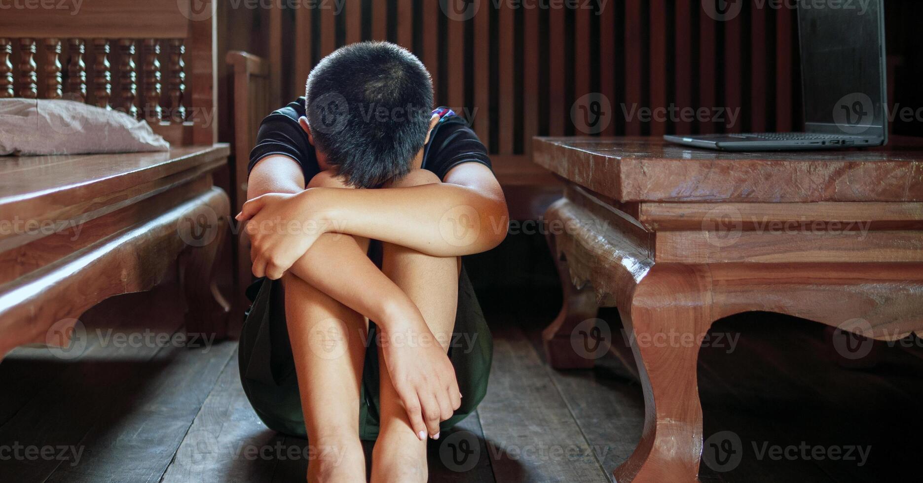 Asian kid boy Upset, sitting in the dark, thinking about conflicts, family relationships. sad face, Unhappy child sitting with head down, Emotion sad and sad face, depression children concept photo