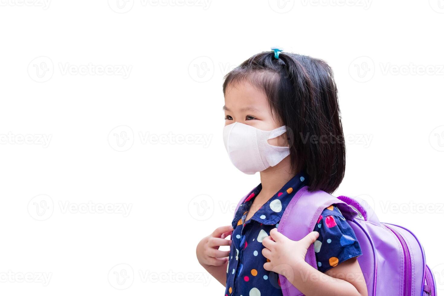 Protected little girl wearing a surgical face mask for flu and virus protection in healthcare, Children preparing to go to summer school, Kid carrying purple bags. photo