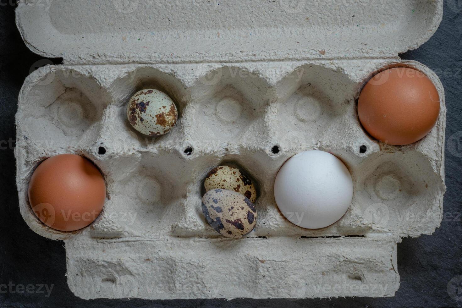 Fresh quail and chicken eggs in a paper tray, top view selective focus photo