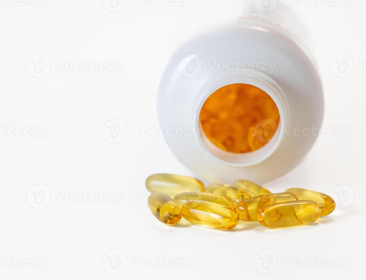 Yellow fish oil capsules in a jelly shell near the white jar photo