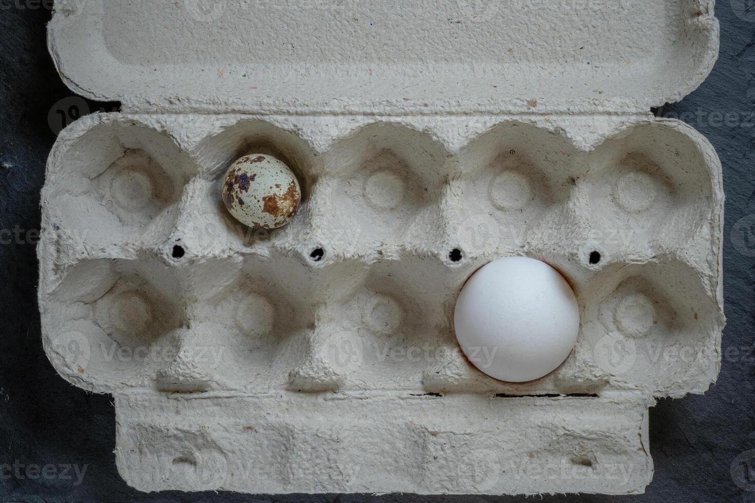 Fresh quail and chicken eggs in a paper tray, top view selective focus photo