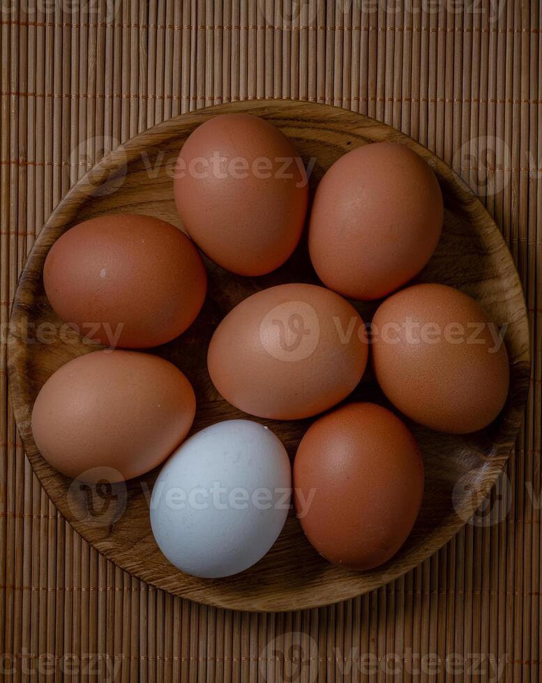 Fresh chicken eggs in wooden plate on the table, selective focus photo