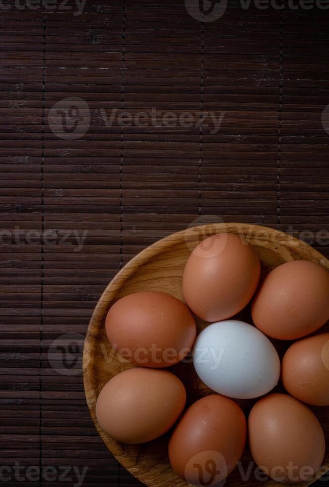 Fresh chicken eggs in wooden plate on the table, selective focus photo