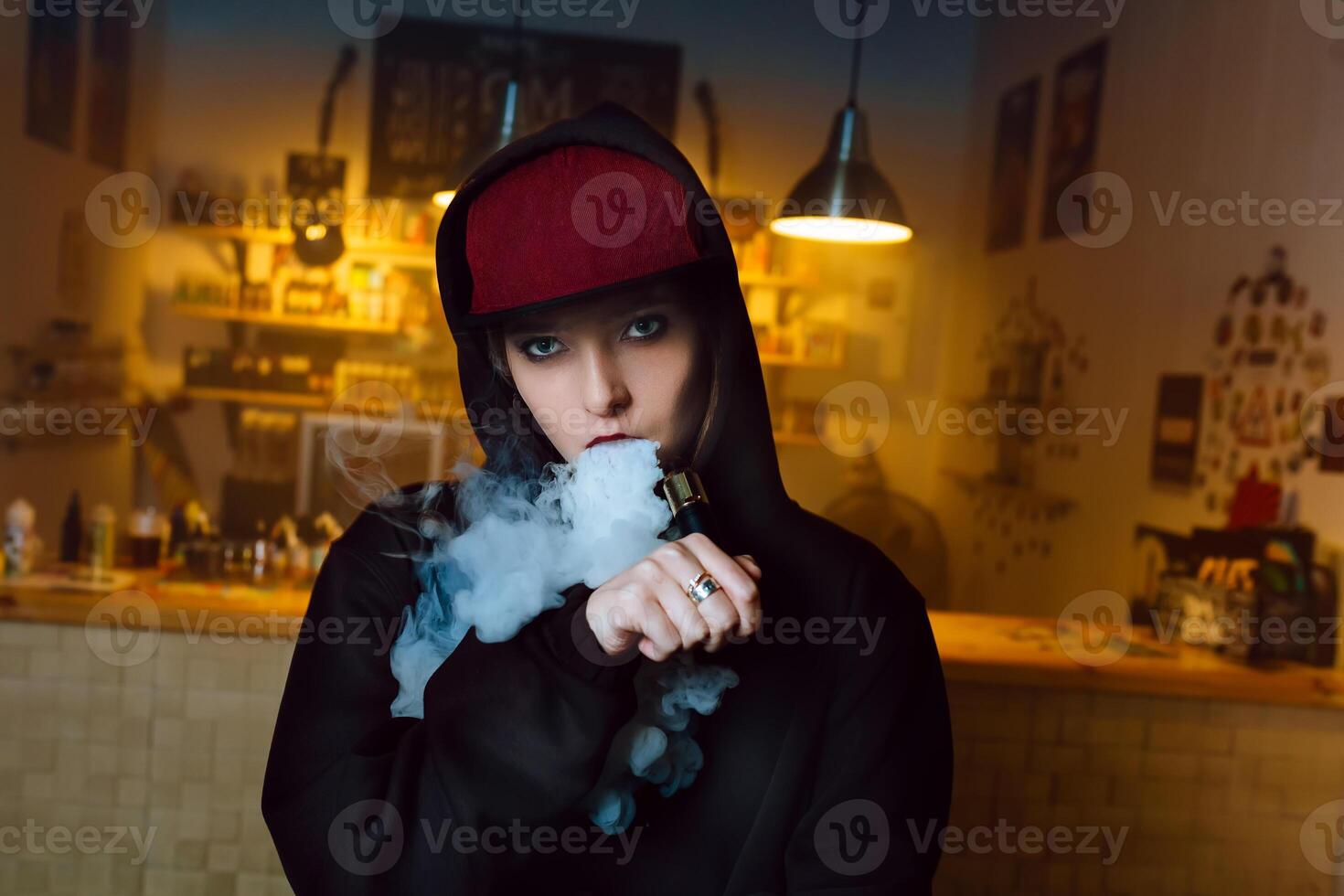 vaping muchacha. joven hipster mujer vape e-cig a el tienda de vaporizadores. hip hop estilo. de cerca. foto