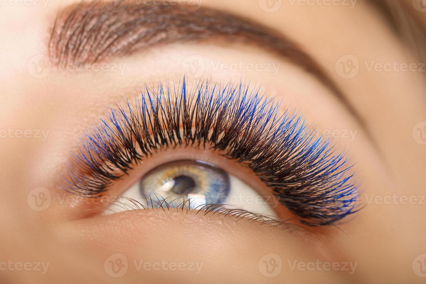 Eyelash Extension Procedure. Woman Eye with Long Blue Eyelashes. Ombre effect. Close up, selective focus. photo