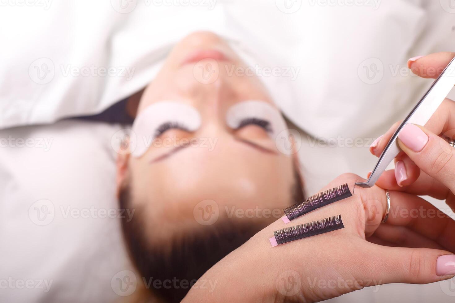 Eyelash Extension Procedure. Woman Eye with Long Eyelashes. Close up, selective focus. photo