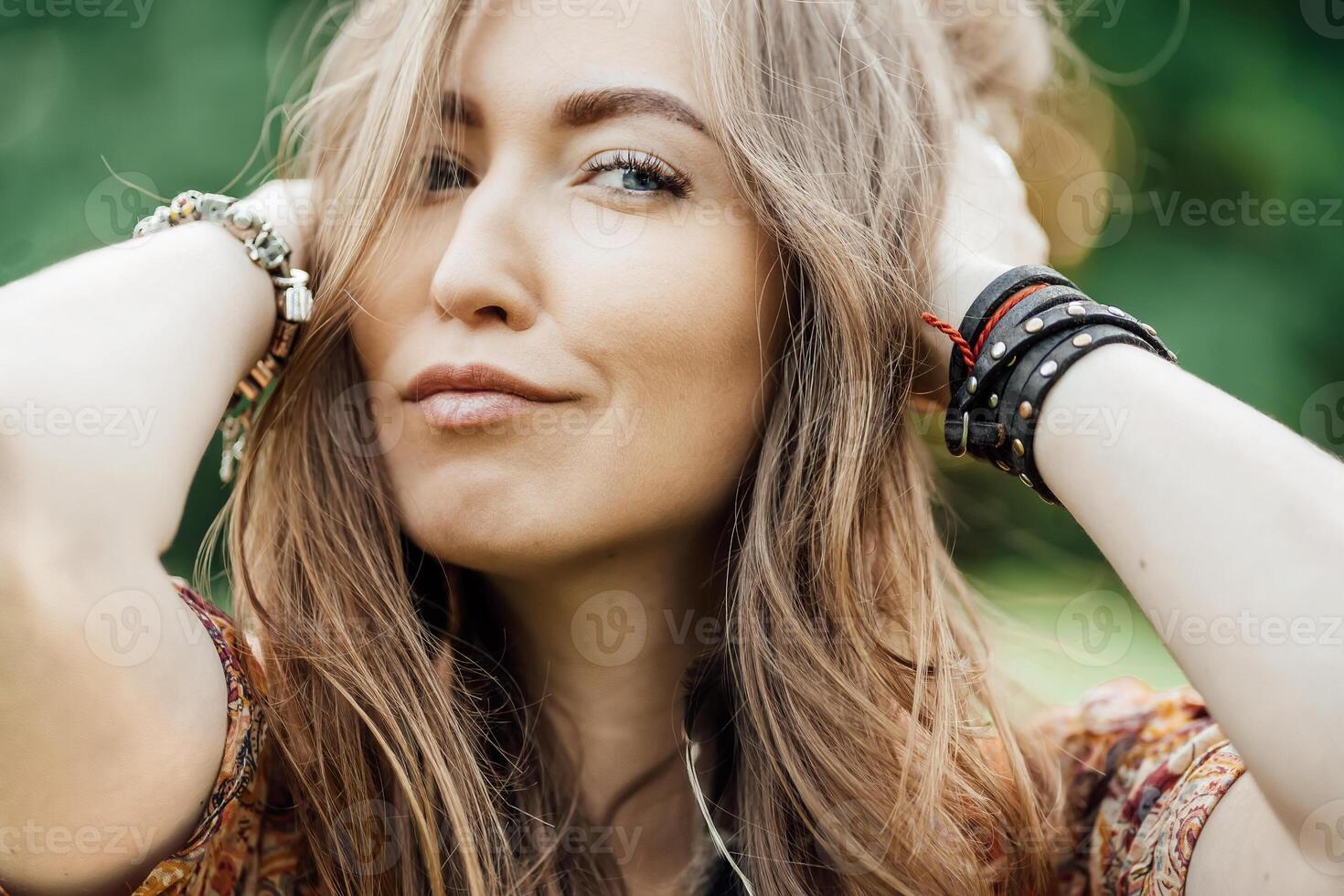 Close up Beautiful young woman wearing bohostyle clothes posing in the rays of the evening sun, sunset. Boho style fashion, female wearing silver jewelry having fun in park outdoors. photo