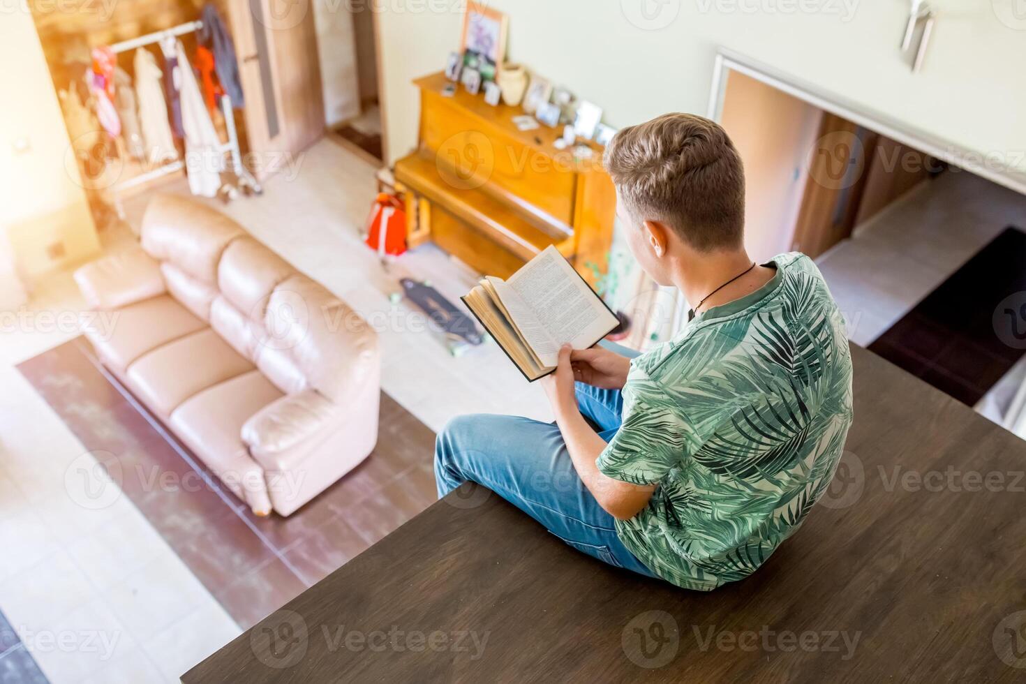 el adolescente es leyendo un libro, sentado en el segundo piso de el casa. parte superior ver de el habitación. selectivo enfocar. foto