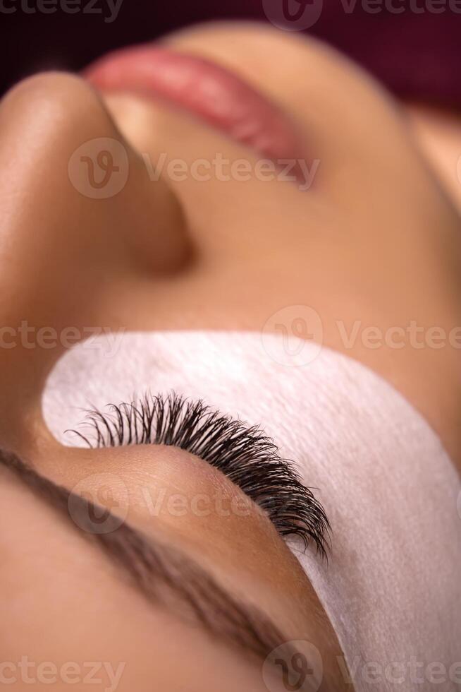Eyelash Extension Procedure. Close up view of beautiful female eye with long eyelashes, smooth healthy skin. photo