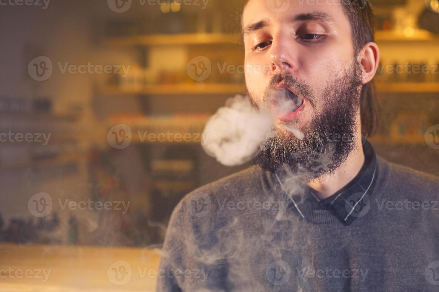 hombres con barba vaping y lanzamientos un nube de vapor. de cerca. foto