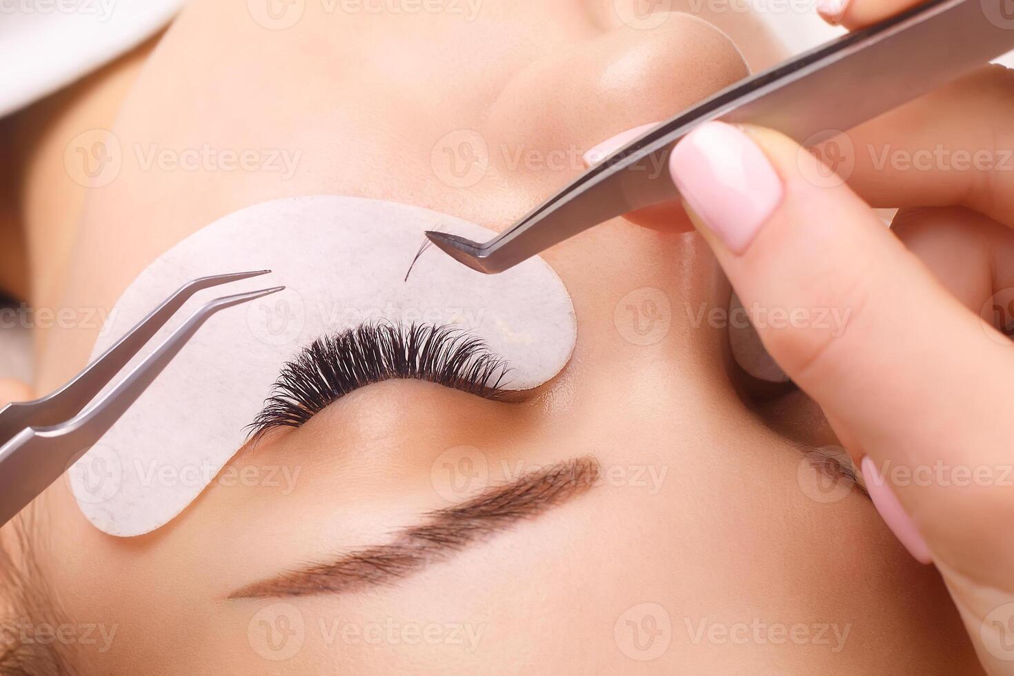Eyelash Extension Procedure. Woman Eye with Long Eyelashes. Close up, selective focus. photo