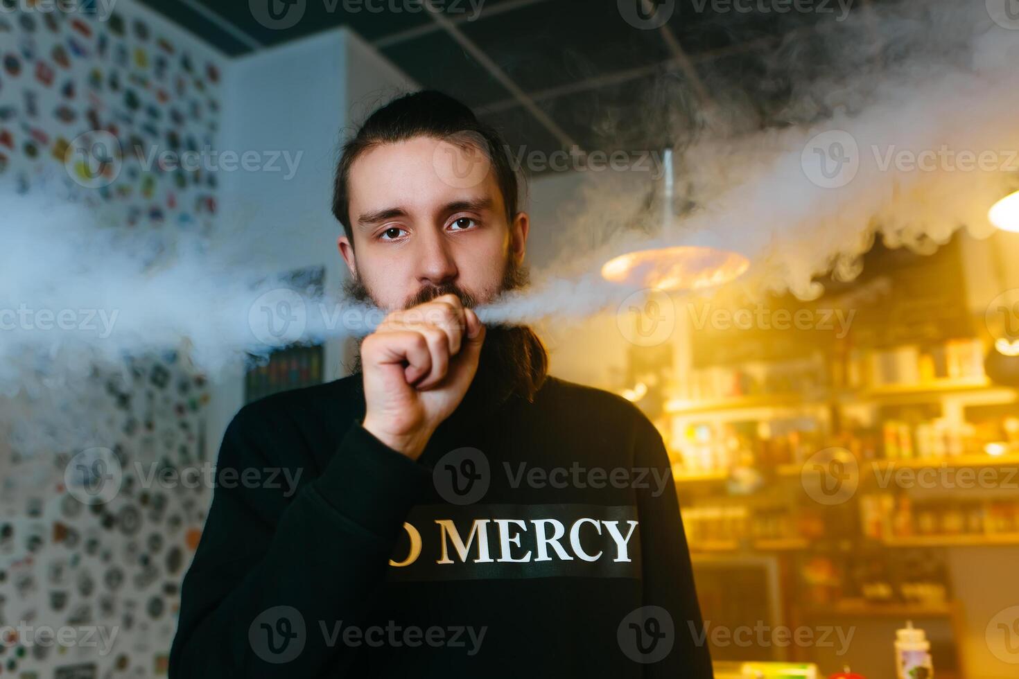 joven hombres con barba vaping y lanzamientos un nube de vapor. de cerca. foto