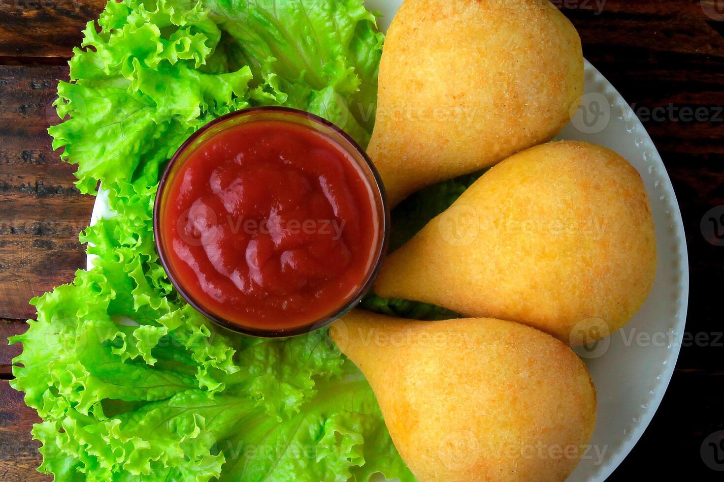 coxinha en el plato, tradicional brasileño cocina meriendas relleno con pollo, en rústico de madera mesa foto