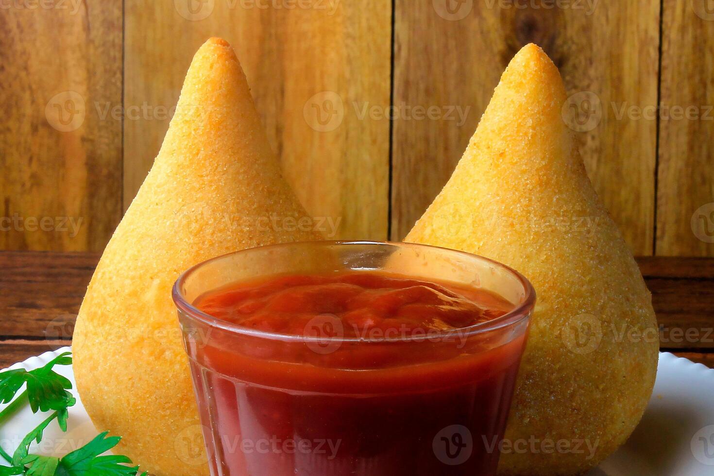 coxinha en el plato, tradicional brasileño cocina meriendas relleno con pollo, en rústico de madera mesa foto