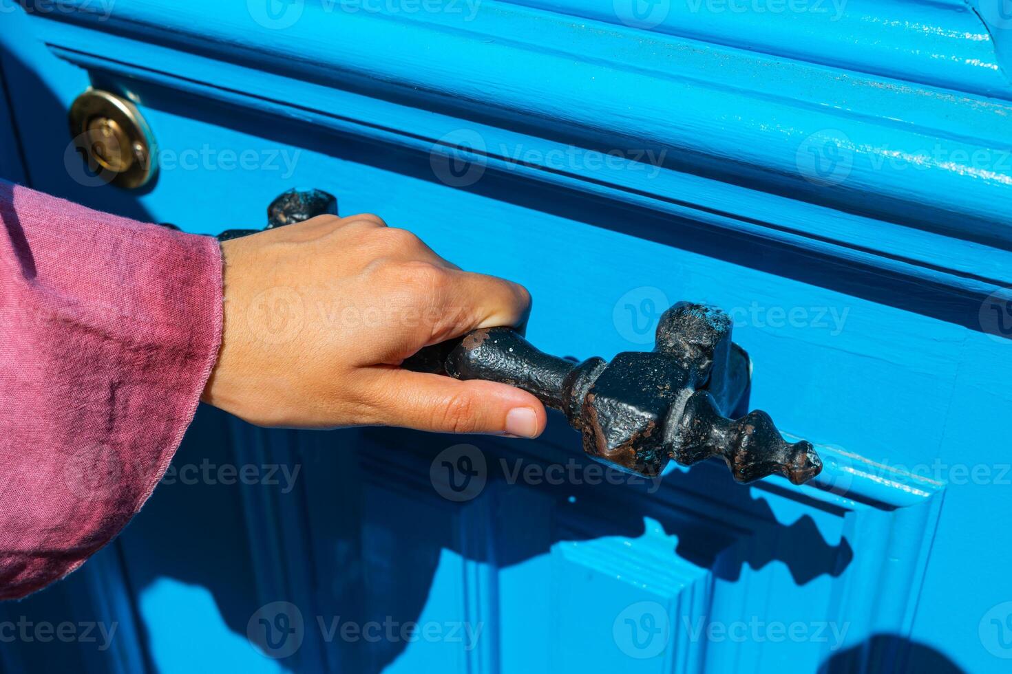 Woman holding a vintage rusty door handle to enter the house photo