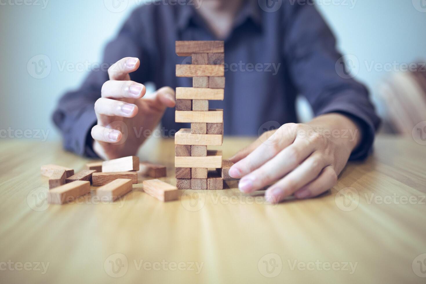 Business strategy concept with hands playing a wooden block tower game, symbolizing risk and stability. Planning risk management photo