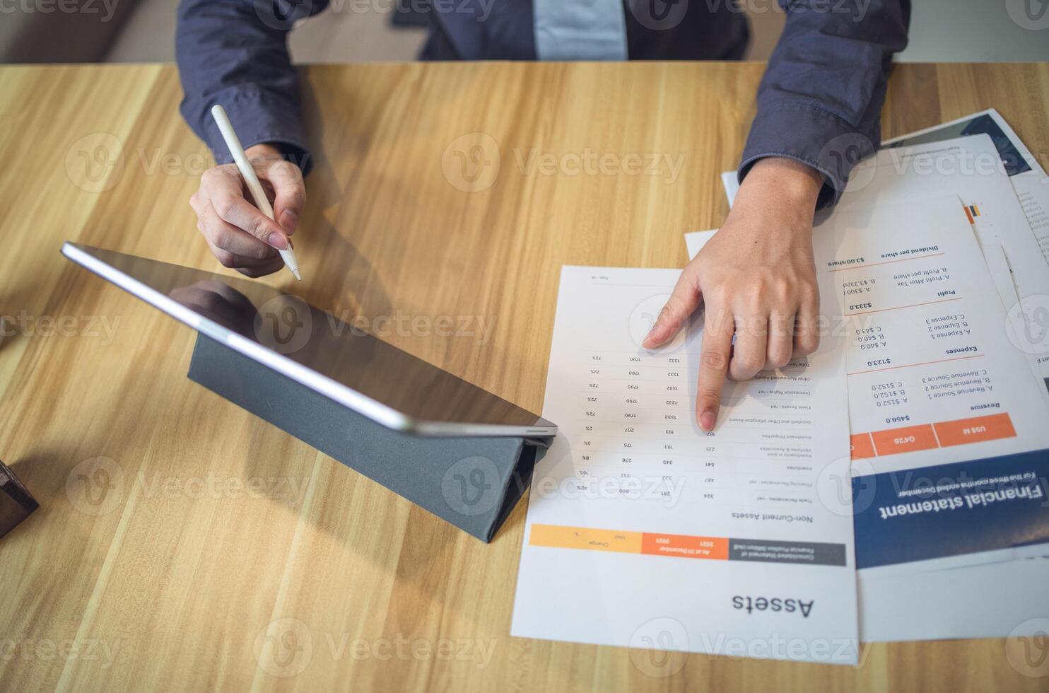 Businessman analyzing bar graph data with pen in hand, laptop and coffee on desk. Business concept photo