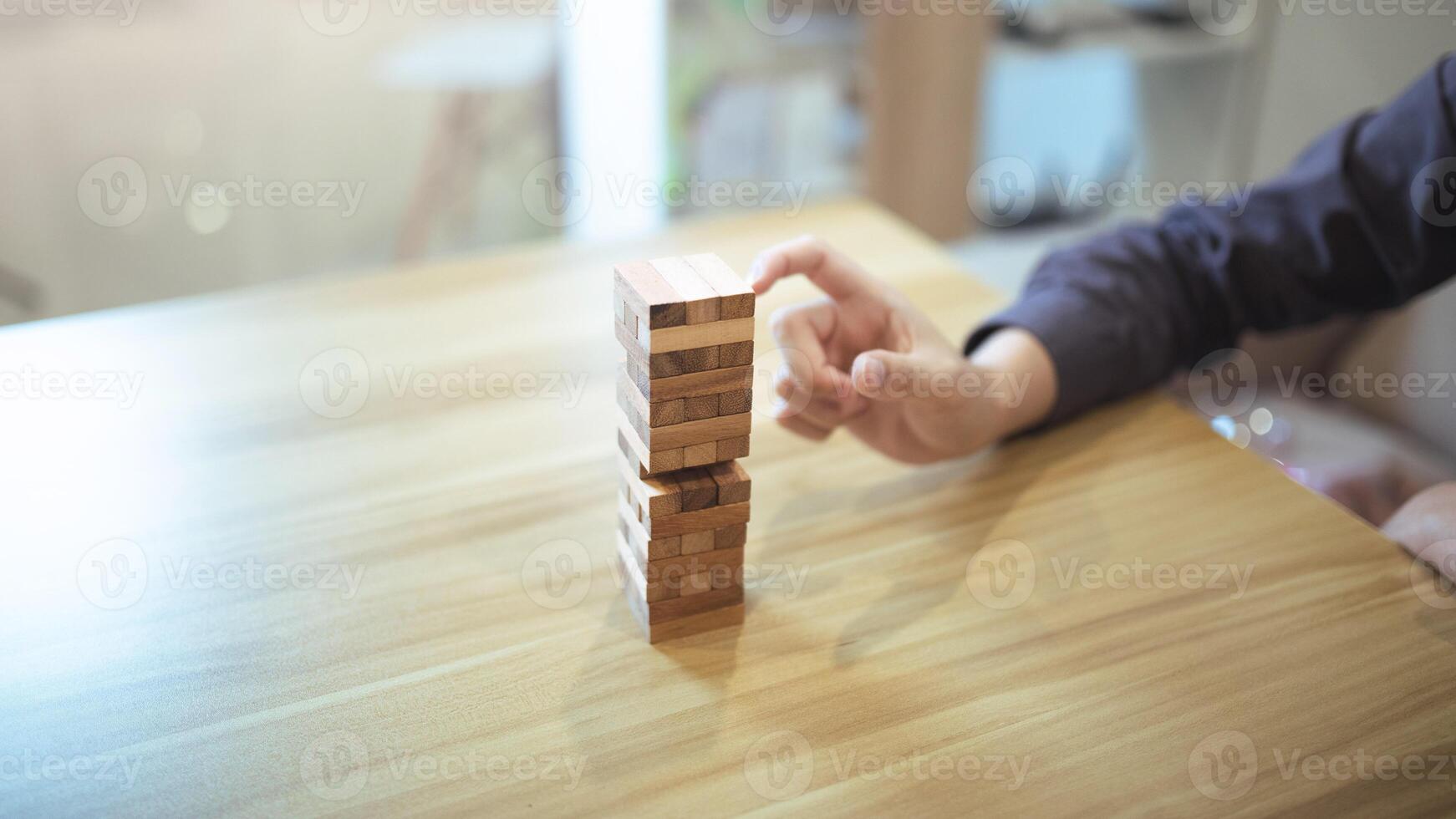 Business strategy concept with hands playing a wooden block tower game, symbolizing risk and stability. Planning risk management photo