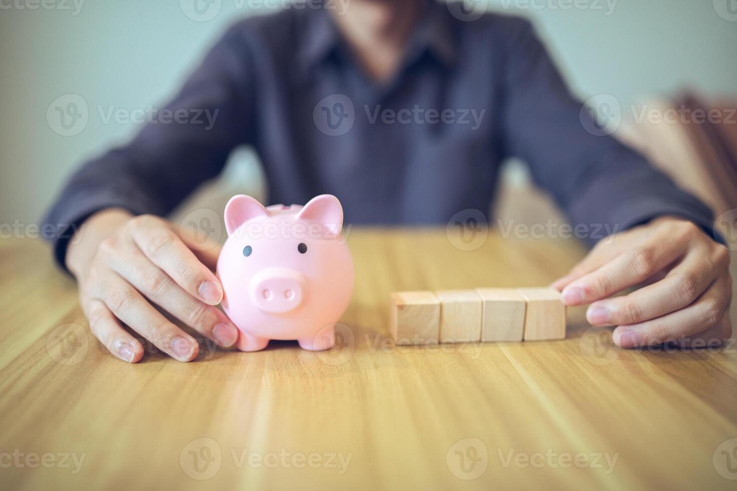 un persona con un cerdito banco y de madera bloques en un mesa, ilustrando conceptos de ahorros y inversión foto