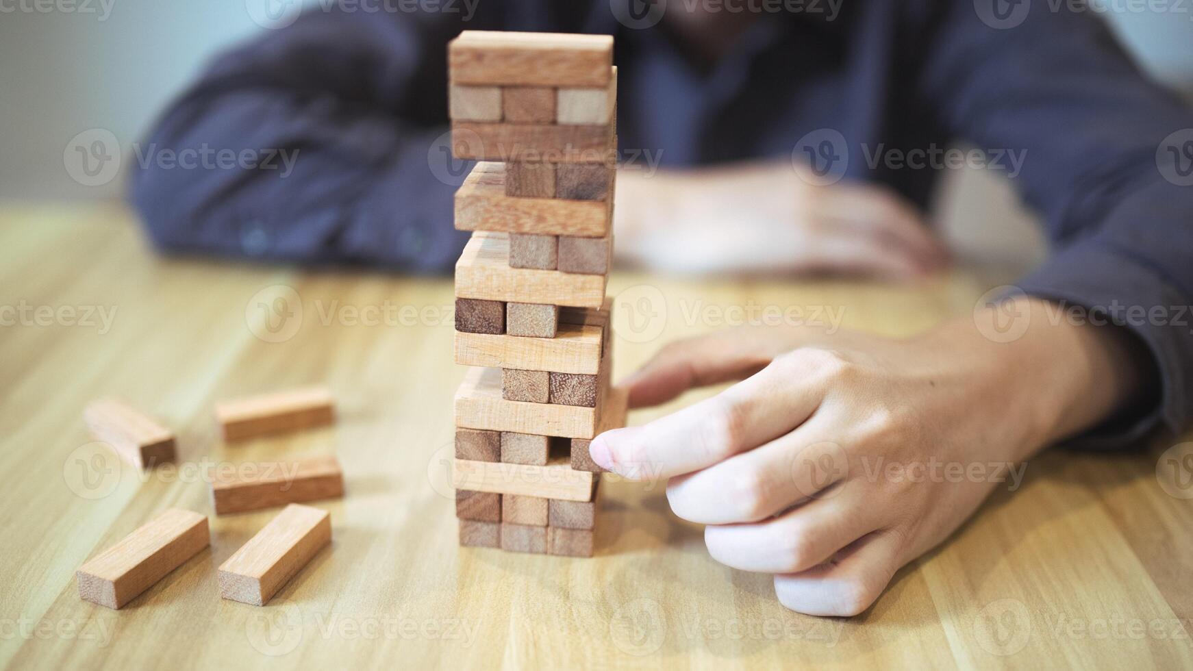 Business strategy concept with hands playing a wooden block tower game, symbolizing risk and stability. Planning risk management photo