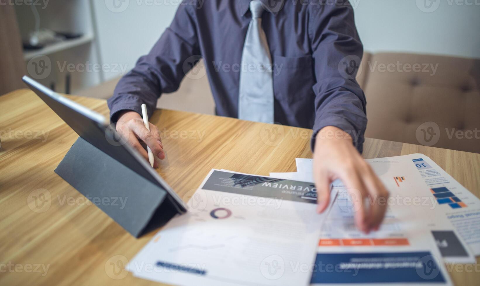 Businessman analyzing bar graph data with pen in hand, laptop and coffee on desk. Business concept photo